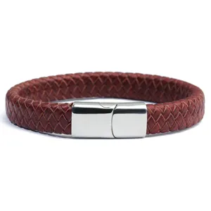 Close-up van de gevlochten bruine lederen armband met gladde roestvrijstalen magnetische sluiting.