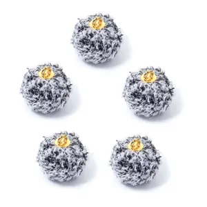 Primer plano detallado de pompones rizados suaves en blanco y negro con anillas de metal dorado.
