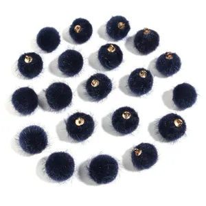 Close-up of dark blue furry pom pom charms with gold loops for DIY jewelry and crafts.