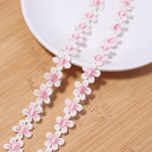Detailed shot of white pink daisy lace trim embroidery, perfect for DIY clothing and crafts.