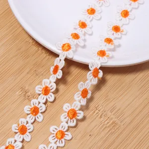 Close-up of white and orange daisy embroidery lace trim for DIY crafts and clothing decor.
