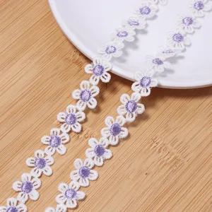 Detailed close-up view of white and purple daisy water-soluble lace embroidery trim material.