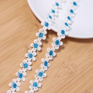 Detailed shot of white and blue embroidered daisy lace trim, perfect for DIY crafts and clothing.