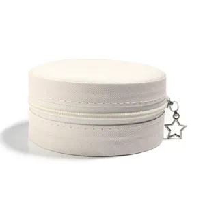 Detailweergave van de ronde, beige PU lederen sieradendoos met een ster vormige rits.
