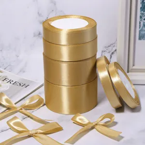 Rotoli di nastro in raso dorato e fiocchi artigianali per confezioni regalo e decorazioni fai da te.