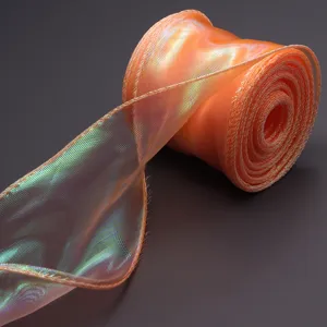 Close-up detail of shimmering iridescent orange organza ribbon roll for wrapping and decor.