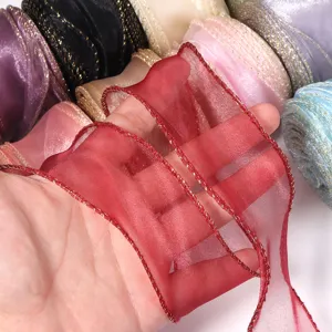 Primo piano dettagliato di nastro in organza trasparente con bordo dorato e filo metallico.
