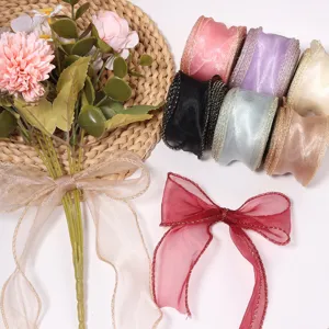 Nastri in organza trasparente con bordi dorati, bouquet di fiori decorativo e fiocchi.