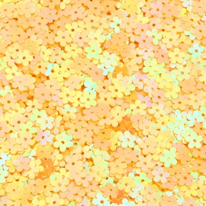 Close up detail shot of small iridescent flower sequins in yellow and orange, ideal for DIY crafts.