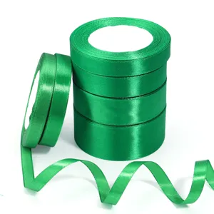 Nastro di raso verde nel dettaglio, rotolo di tessuto strutturato per confezioni regalo fai da te.