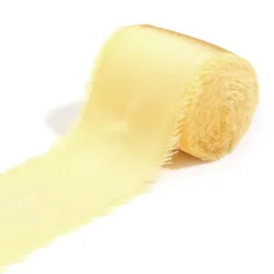 Primo piano di un rotolo di nastro di raso giallo chiaro con bordi sfrangiati e finitura.