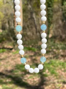Primo piano dettagliato della collana di perle blu e bianche con delicati distanziatori d'oro.