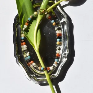Primo piano dettagliato di collana di perle in pietra naturale su vassoio argentato.