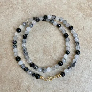Dettaglio della collana di perline in pietra naturale che mette in mostra le perle nere.