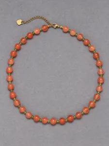 Primo piano dettagliato della collana di perle colorate, con delicate pietre naturali rosa e verdi.