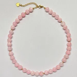 Dettaglio in primo piano della collana di perle di cristallo rosa con distanziatori oro.