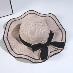 Detailed display of summer women straw sun hat with black ribbon bow and wavy brim style.