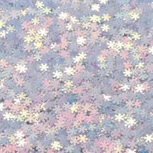 Holographic snowflake PVC sequins detail, macro shot of shiny nail art glitter and craft supplies.