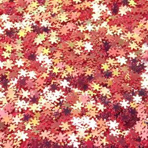 Close-up detail of red and gold holographic snowflake sequins for nail art and diy.