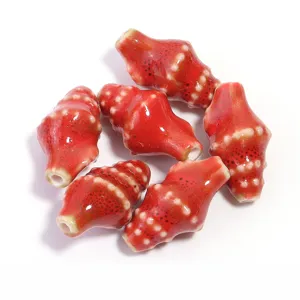 Ceramic conch beads close-up, glossy red glazed finish with white speckles, DIY handmade parts.