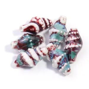 Detailed close-up of handmade ceramic conch beads with stunning glaze variation designs.