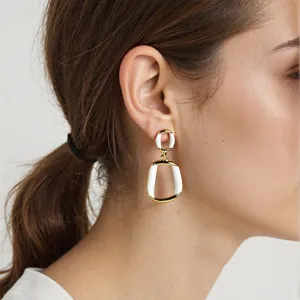 Eleganti orecchini geometrici dorati in acciaio inossidabile con design a smalto bianco.