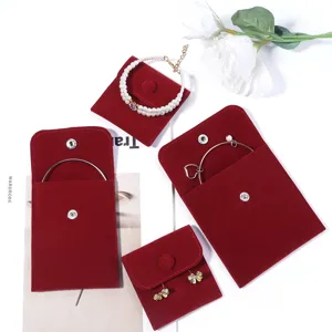 Detail view of red velvet jewelry storage pouches with snap buttons for travel organization.