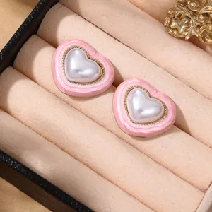 Detailaufnahme von stilvollen rosa Herz-Ohrringen mit einer weißen Perle und feinem Goldrand.