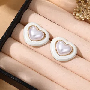 Schicke kontrastierende Herz-Ohrstecker mit Perlenmitte und Goldperlen für Damen.
