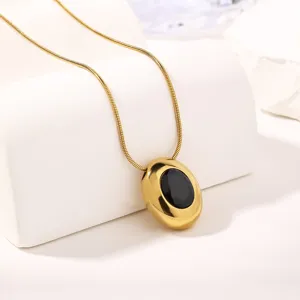 Gold snake chain necklace featuring an oval metal pendant with a black faceted zircon.