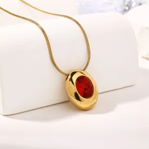 Gold snake chain necklace with vibrant red oval cubic zirconia pendant detail shot.