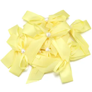 Dettaglio fiocco nastro giallo con perla a cuore al centro per accessori capelli.
