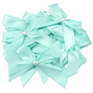 Primo piano di fiocchi in nastro di raso verde menta con perle a cuore bianche, accessorio fai da te.
