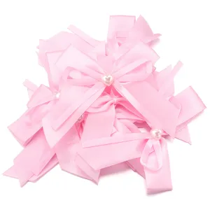 Dettaglio fiocchi nastro raso rosa, perla cuore, accessori capelli DIY e rifiniture abiti.