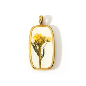 Detail van hars hanger met gedroogde gele bloemen, vintage gouden lijst accessoire macro.