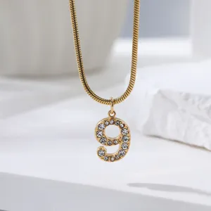 Gedetailleerd uitzicht van de gouden slangketting met schitterende strass nummer 9 hanger.