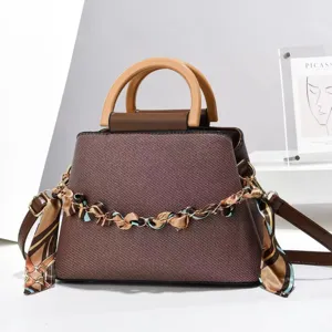 Vue détail du sac à main marron élégant avec poignée en bois et chaîne décorative.