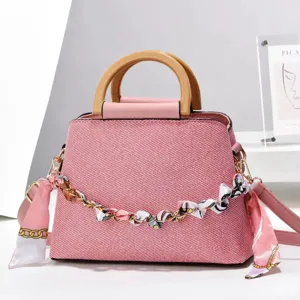 Sac à main rose texturé avec poignées en bois, chaîne métal et foulard soie décoratif.