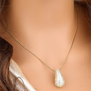 Gros plan d'un collier chaîne serpent dorée avec un pendentif goutte étincelant.