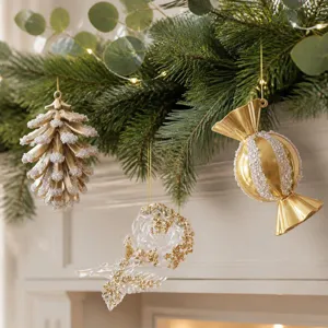Dettagli in primo piano di ornamenti sospesi per albero di Natale dorati, pigna, caramella e fiori.