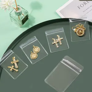 Sachets zip transparents en PVC avec divers pendentifs croisés et médaillons en strass scintillants.