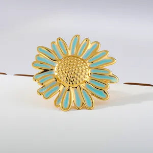 Detailed shot of gold-plated daisy flower ring with turquoise enamel finish and sparkling texture.