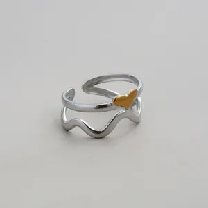 Detailansicht des Edelstahlrings mit doppeltem Band, goldenem Herz und wellenförmigem Design.