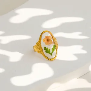 Detailed shot of gold-plated stainless steel ring featuring a clear resin preserved flower design.