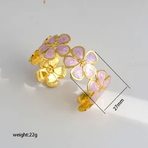Gold open cuff bracelet with pink enamel flower details, elegant floral jewelry piece.