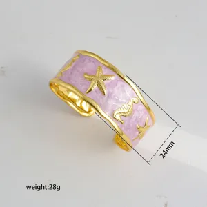 Gold plated open cuff bracelet featuring pink enamel finish, starfish and seahorse motifs, 24mm.
