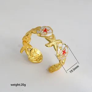 Gold open cuff bracelet with enameled seashell and starfish design, elegant fashion jewelry.