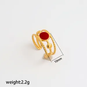 Detailed shot of stainless steel adjustable ring with red enamel and twisted gold bands.