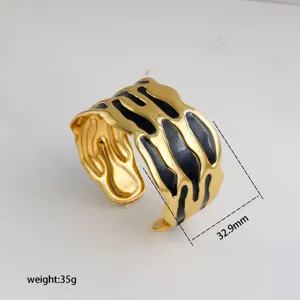 Gold open cuff bracelet with black enamel detail, irregular molten metal design, stylish jewelry.