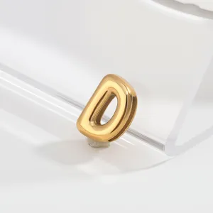 Golden puffy letter D pendant detail shot, minimalist jewelry component macro view.